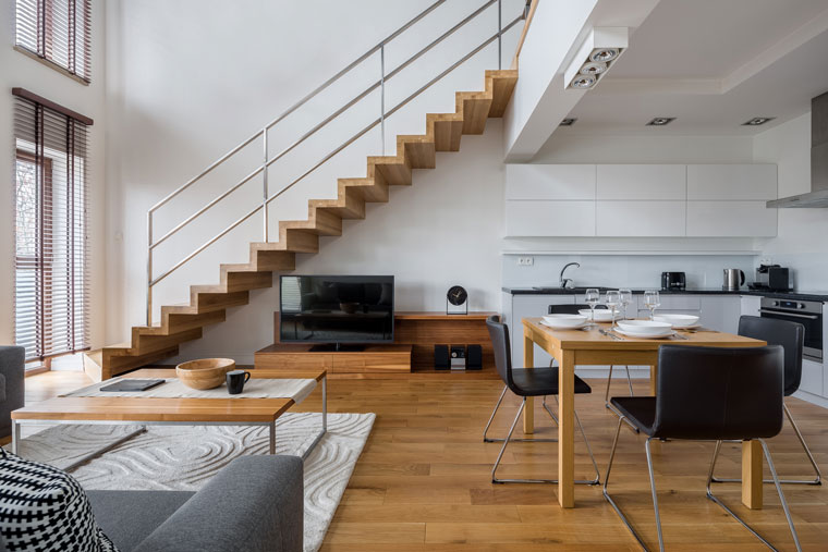 Stilvolle, zweistöckige, offene Wohnung in weiß mit Holzböden, modernen Möbeln und einer Treppe.